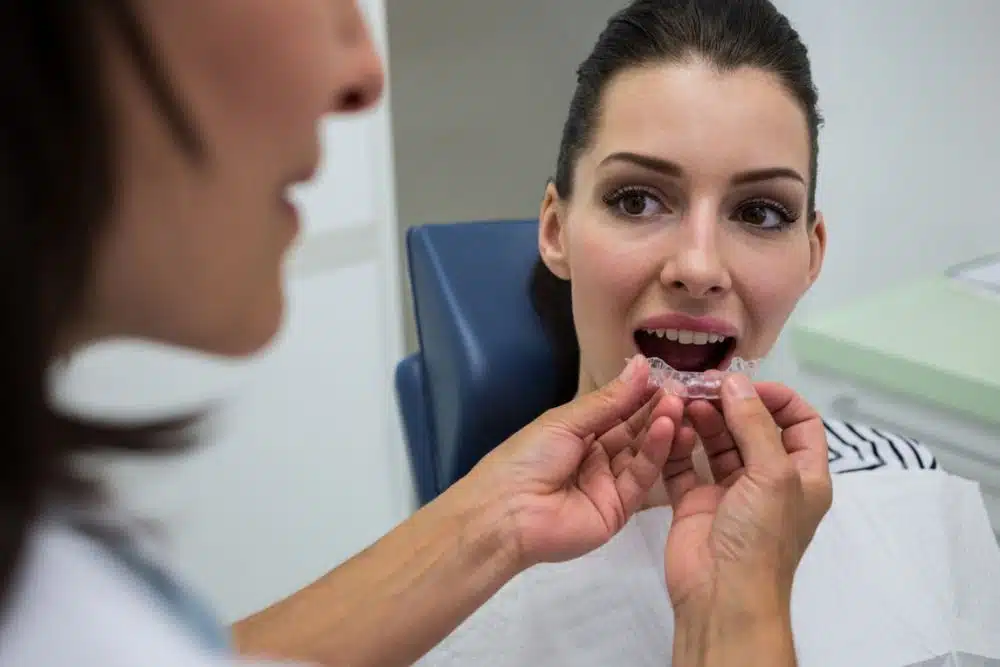 Diş hekimi, hastanın klinikte şeffaf diş hizalayıcısını denemesine yardımcı oluyor